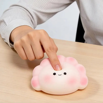 Soft white and pink dumpling squishy fidget toy with a smiling face for stress relief during desk work.