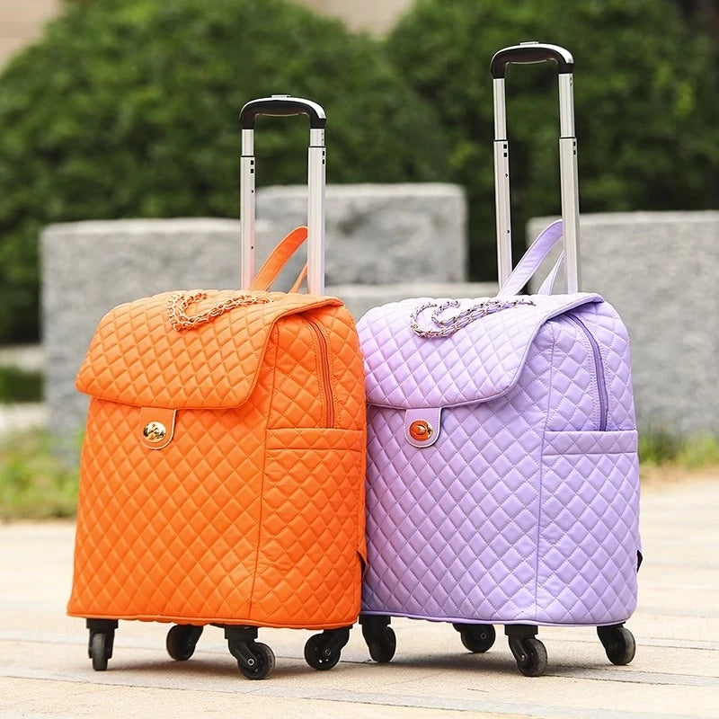 Two quilted PU rolling suitcases in orange and light purple, featuring extendable handles and gold latches.