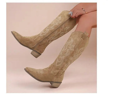 Tan suede knee-high Western boots with block heels and decorative white stitching on the shaft and toe.