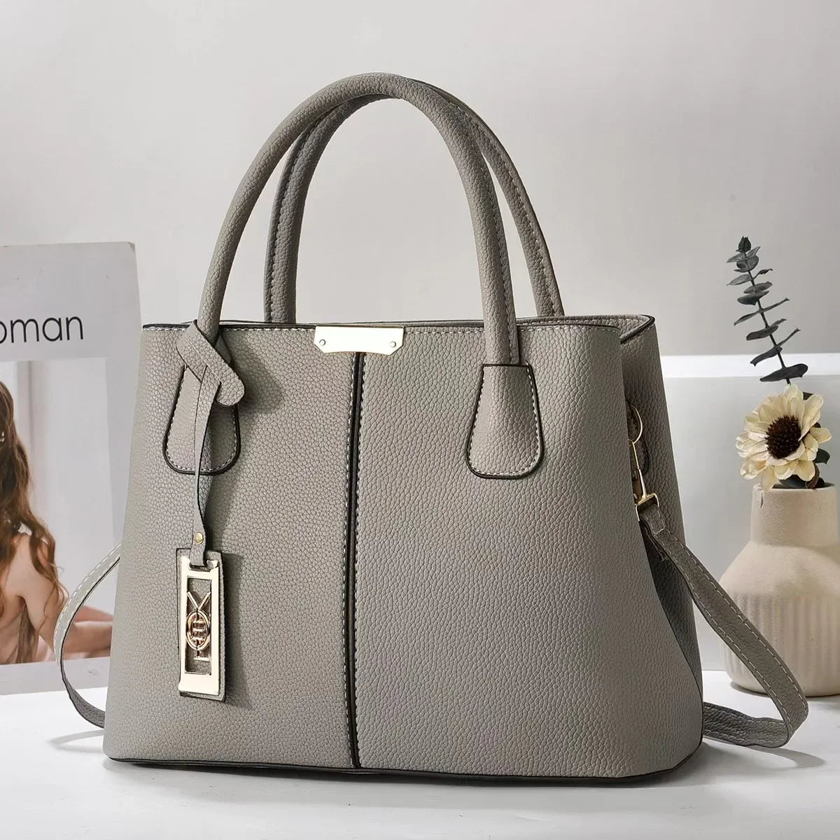 Grey faux leather structured tote bag with gold hardware and zip closure for everyday use.