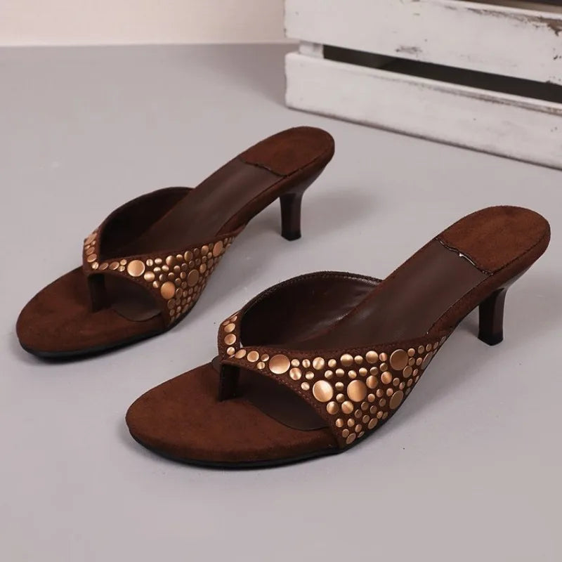 Brown suede stiletto sandals featuring metallic rivet detailing, ideal as slip-on shoes for dressy occasions.