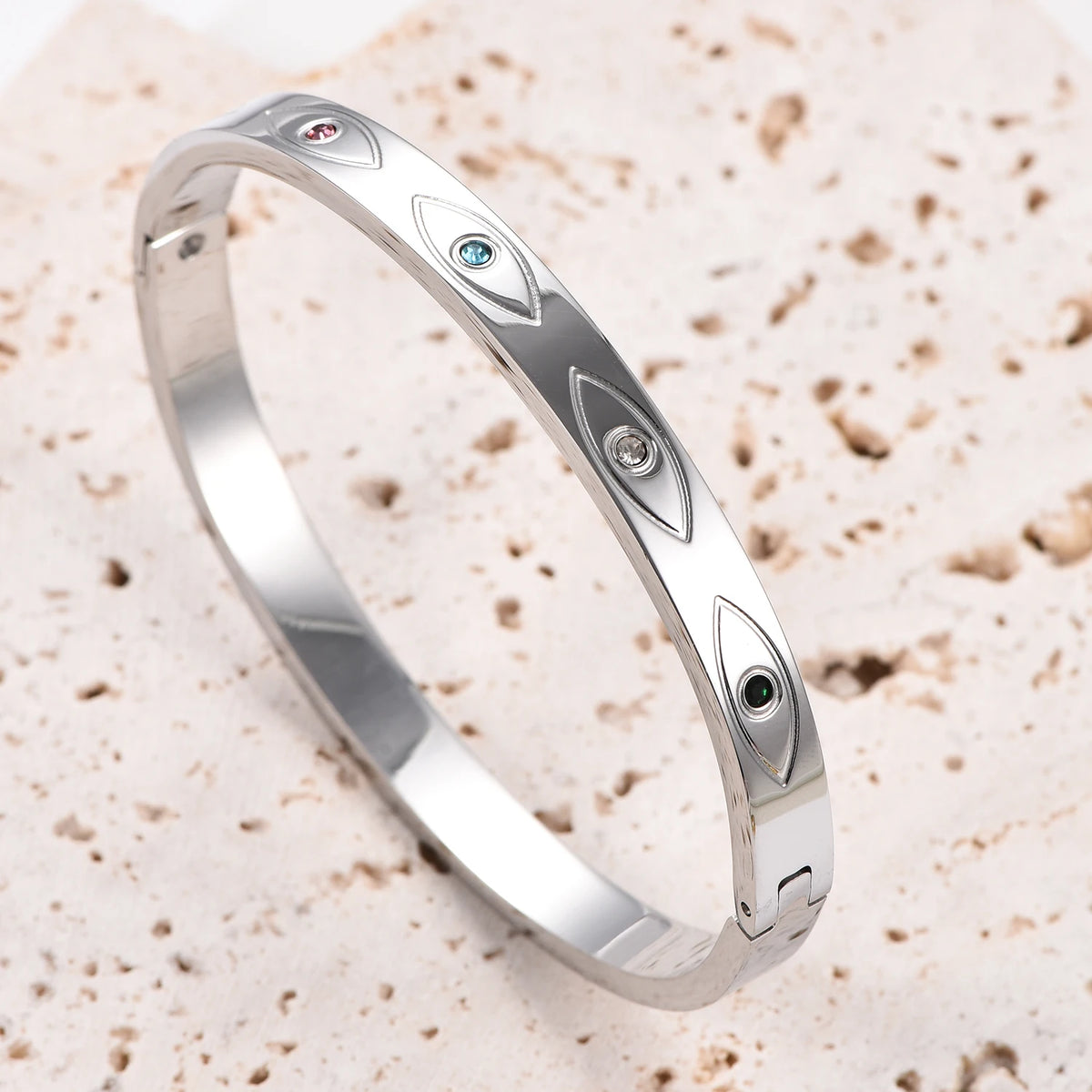 Silver stainless steel cuff bangle with engraved evil eye motifs inset with colorful crystals.