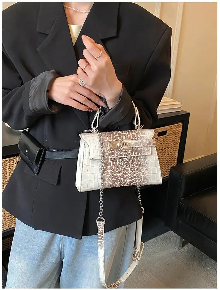 White faux leather structured diaper bag with croc texture, gold hardware, and adjustable strap for carrying baby supplies.