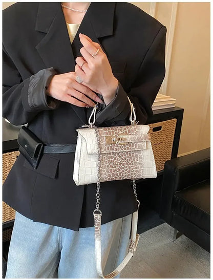 White faux leather structured diaper bag with croc texture, gold hardware, and adjustable strap for carrying baby supplies.