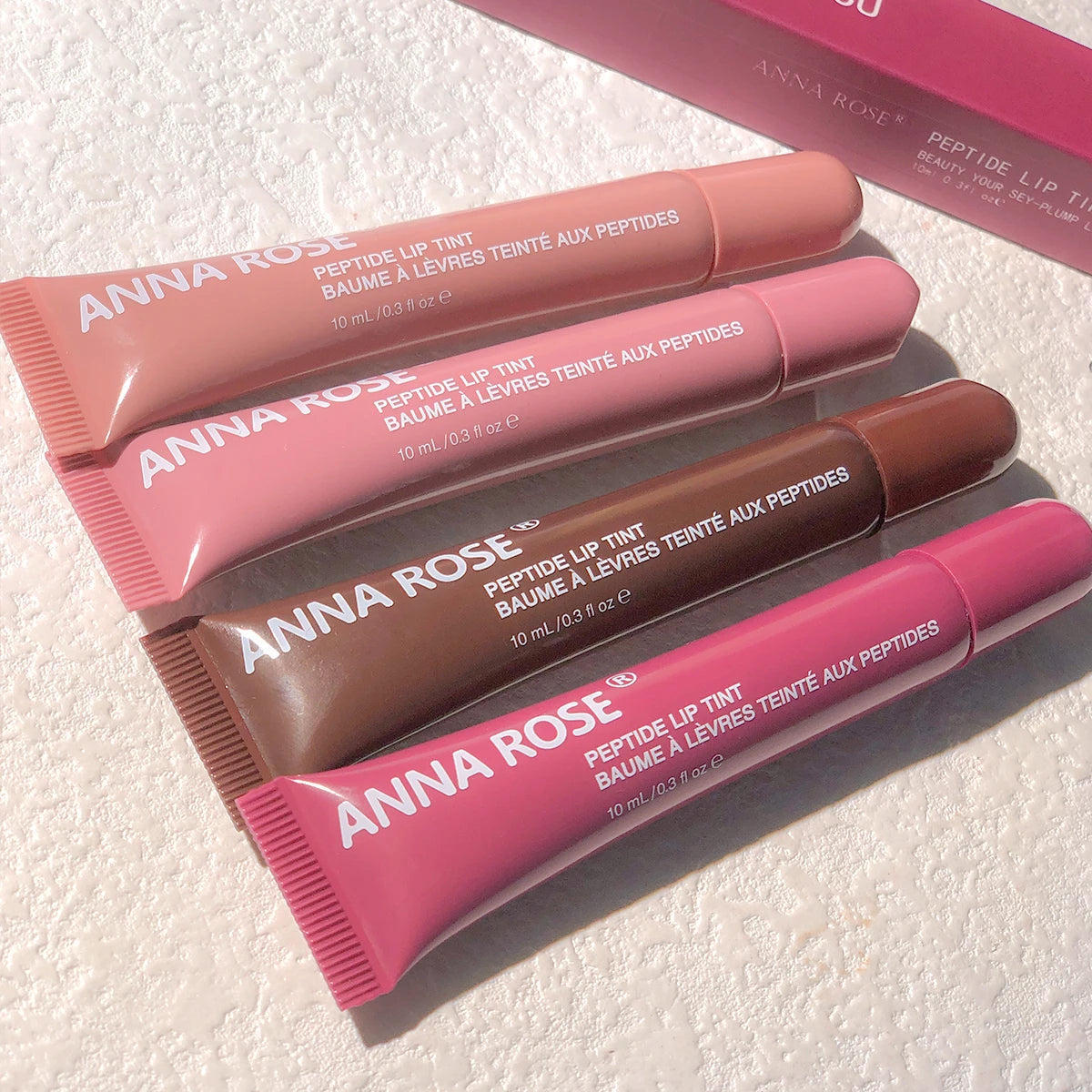 Lip glaze hydrating peptide formula in four squeeze tubes with moisture color.