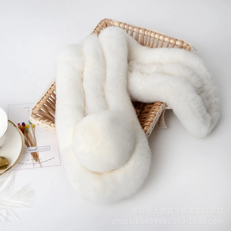 White plush triple-tube rabbit fur scarf with a pom-pom accent in a woven basket.