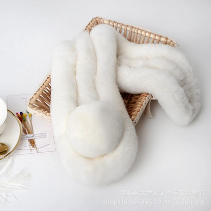 White plush triple-tube rabbit fur scarf with a pom-pom accent in a woven basket.