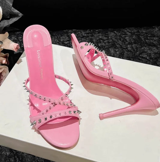 Pink open toe sandals with silver rivets and slim heels, a strappy high heel design for evening wear.