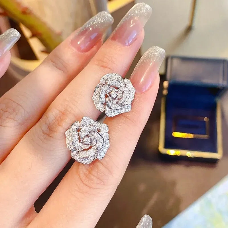 Silver-toned camellia flower stud earrings paved with sparkling clear zircon stones.