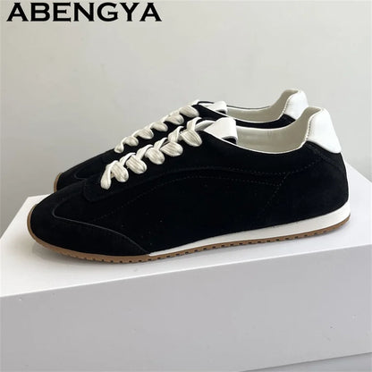 Black suede casual lace-up sneakers with white laces, heel patch, and gum rubber soles.