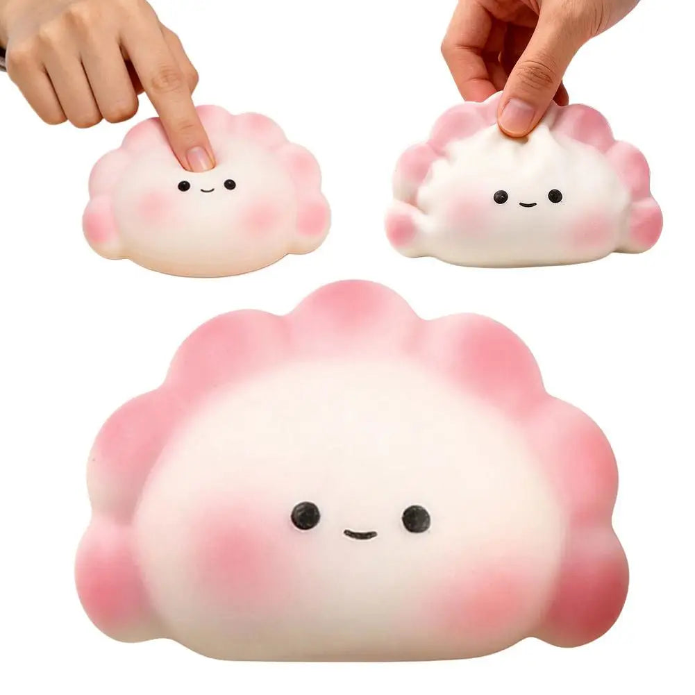 Soft white and pink dumpling squishy fidget toy with a cute face, used as a portable stress relief squeeze toy.