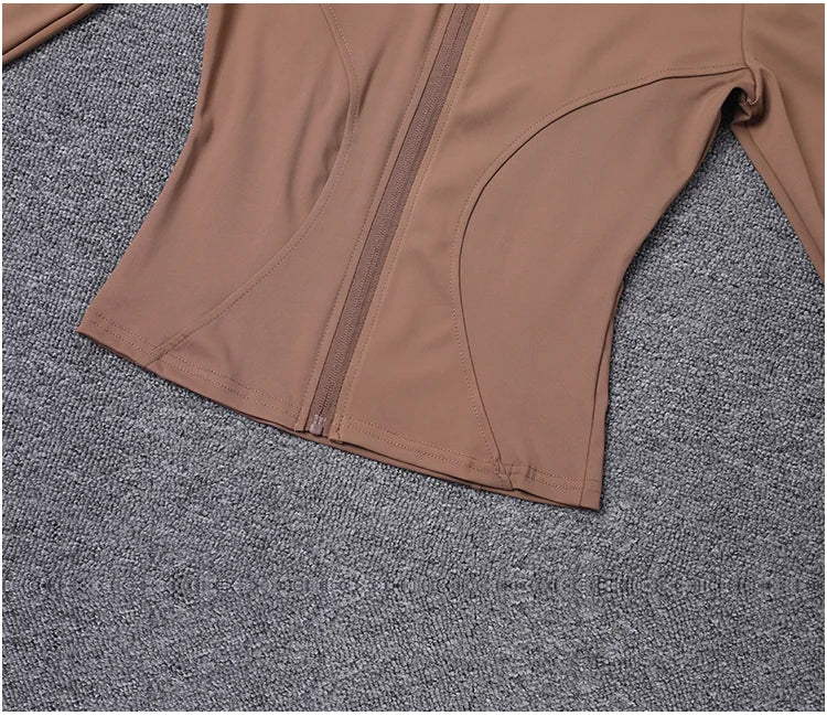 Taupe fitted polyester sport jacket with sculpting seams and zip closure for gym training and yoga.