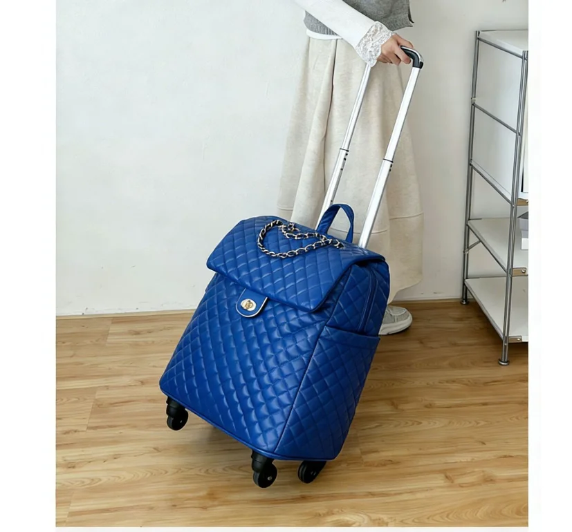 Blue quilted faux leather rolling travel bag with a flap closure, chain accent, and telescopic handle.