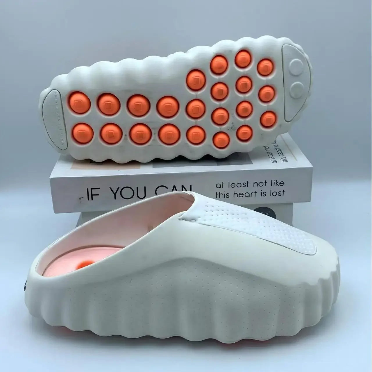 White EVA sandals featuring orange massage nodes on a cushioned non-slip sole for relaxed wear.