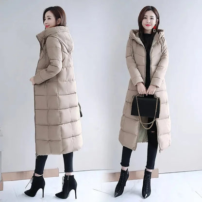 A woman wearing a long, beige, quilted puffer coat with a hooded parka style and zippered front.