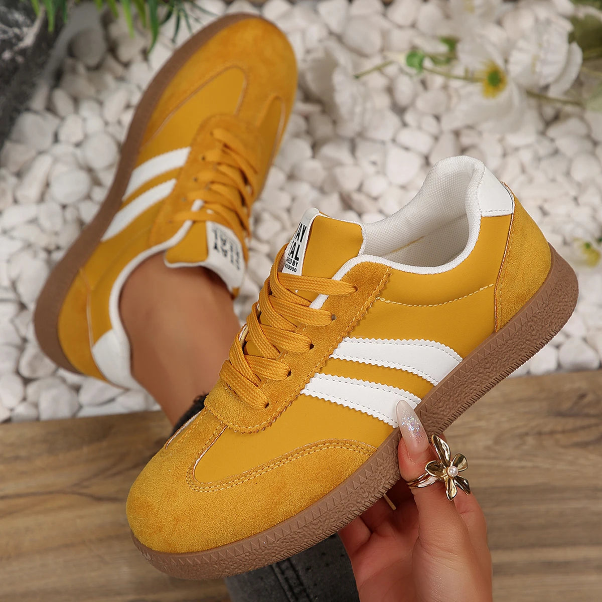 Yellow suede and leather slip-on sneakers with white stripes and brown gum soles for casual daily wear.