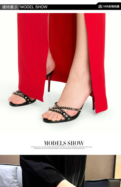 Black strappy slip-on sandals with gold rivets and slim heels, worn with a red dress for a formal event.
