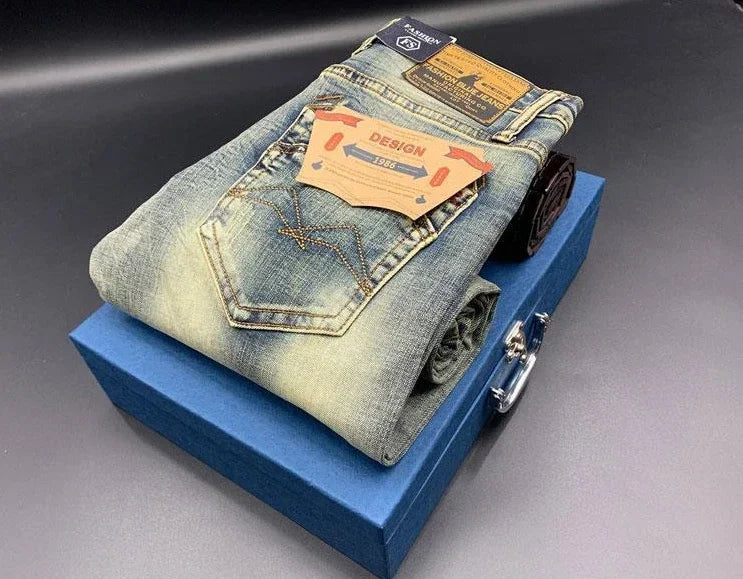 Faded blue stretchy denim tapered jeans with contrast stitching, folded on a blue box for daily wear.