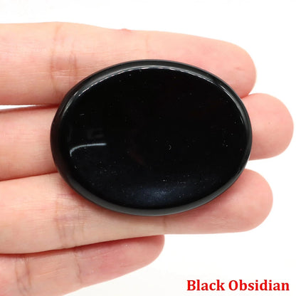 Smooth, oval black obsidian stone held in hand, used as home decor for meditation.