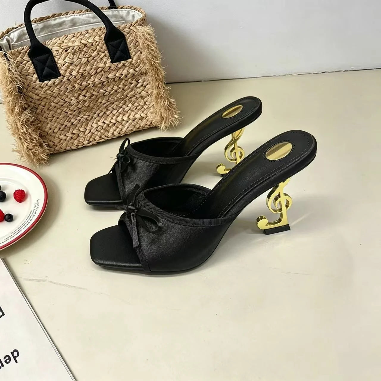 Black satin open toe sandals with a gold music note heel for evening party wear.