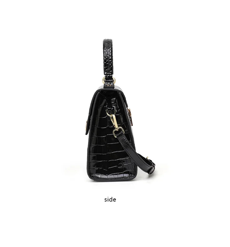 Black patent leather handbag with crocodile pattern, top handle, and gold hardware.