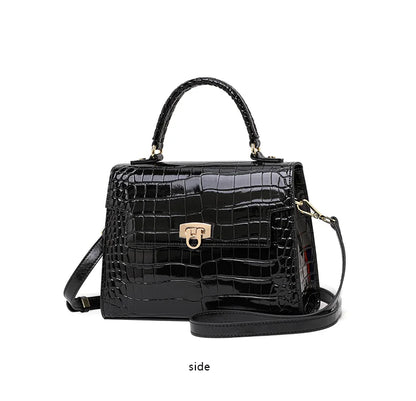 Black patent leather handbag with crocodile pattern, top handle, flap closure, and a crossbody strap.