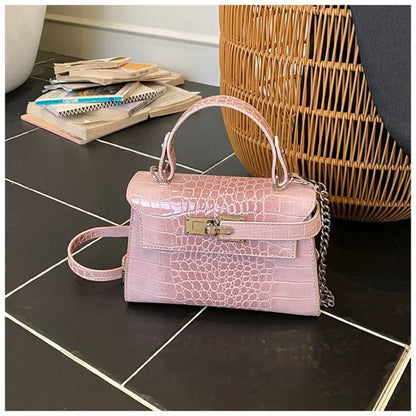 Pink faux leather structured crossbody bag with zip closure and adjustable strap for carrying baby essentials.