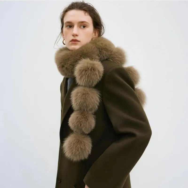 Brown faux fox fur scarf with large pom-poms, worn around the neck of a person in an olive coat.