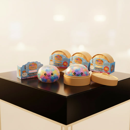 Clear, bead-filled soft foam dumpling fidget toy with a smiling face in a miniature tan bamboo steamer.
