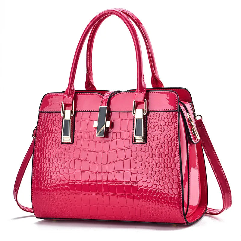Hot pink patent leather crocodile-pattern handbag with dual top handles, gold hardware, and a center clasp.