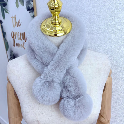Grey plush faux-fur cross scarf with two pom-pom ends on a mannequin.
