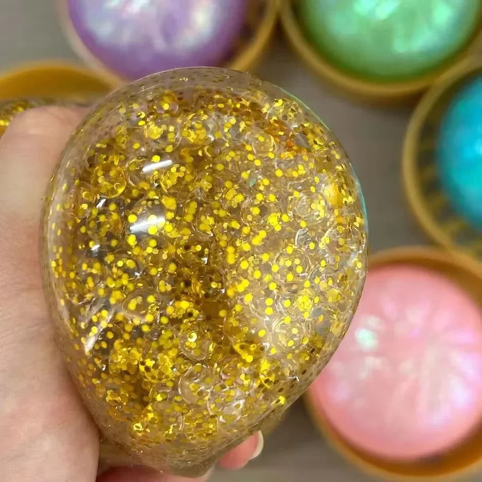 Clear squishy fidget toy filled with gold glitter beads for tactile sensory play.