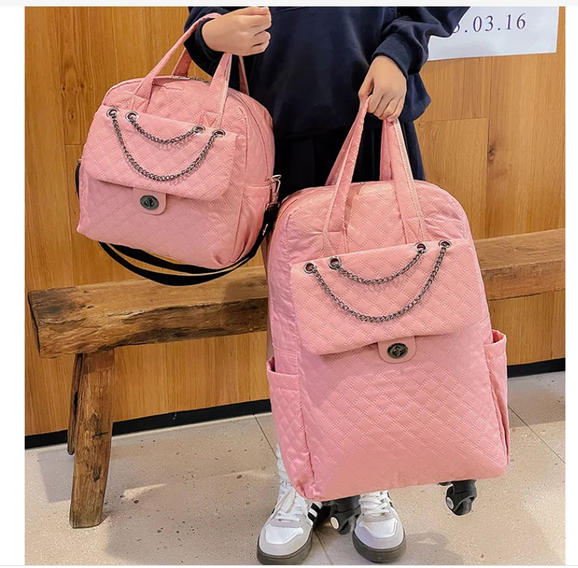 Two pink quilted nylon bags featuring chain-accented front flap pockets, top handles, and twist-lock closures.