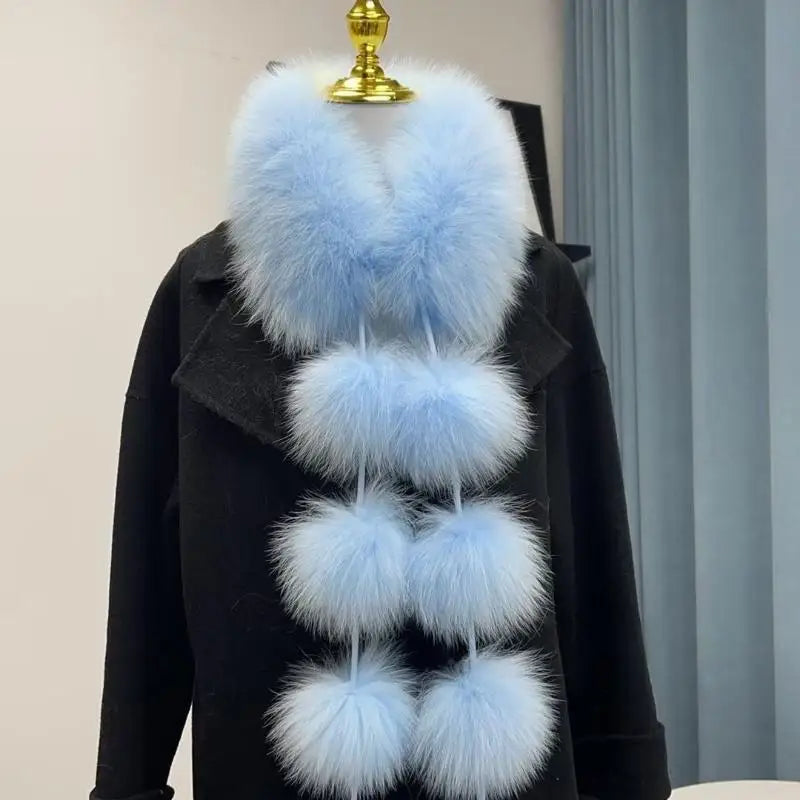 Light blue faux fox fur scarf with six large pom-poms, displayed on a black coat.