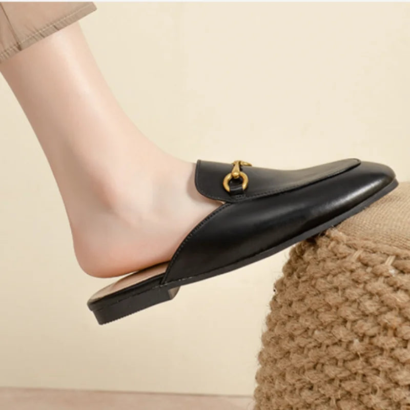 Black closed toe slip-on mules featuring a gold metal chain detail for comfortable outdoor wear.