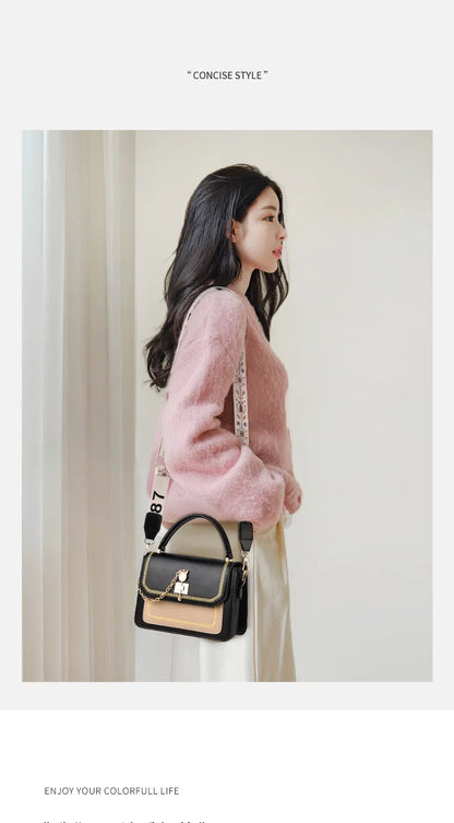 Black and beige leather structured handbag with gold hardware, top handle, and patterned webbing strap.