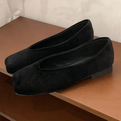 Black suede slip-on flats with square toe and cushioned insoles for daily wear.