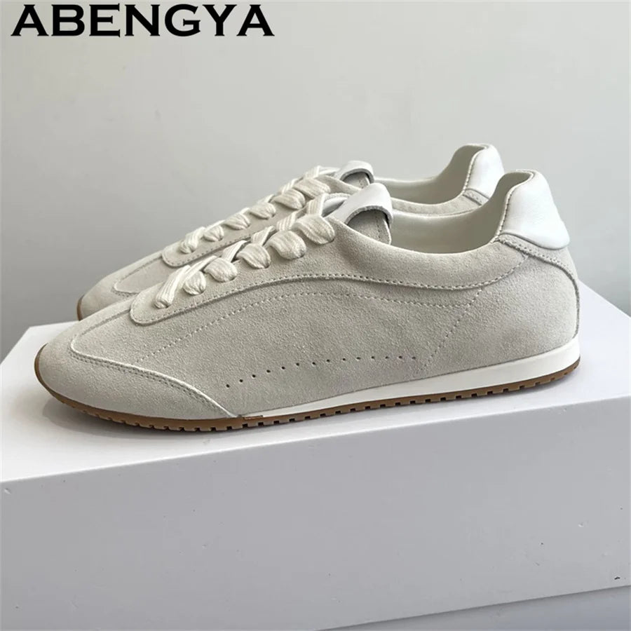 Light gray suede lace-up sneakers with white trim and brown ridged rubber soles.