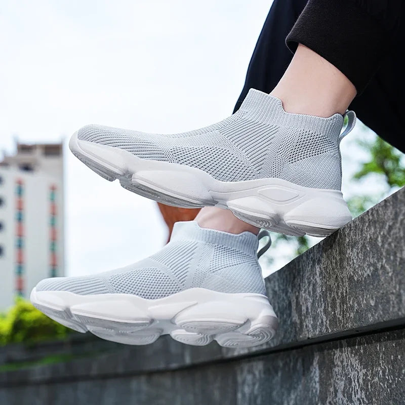 Light gray slip-on sneakers with breathable knit fabric and cushioned white soles for comfortable daily casual wear.