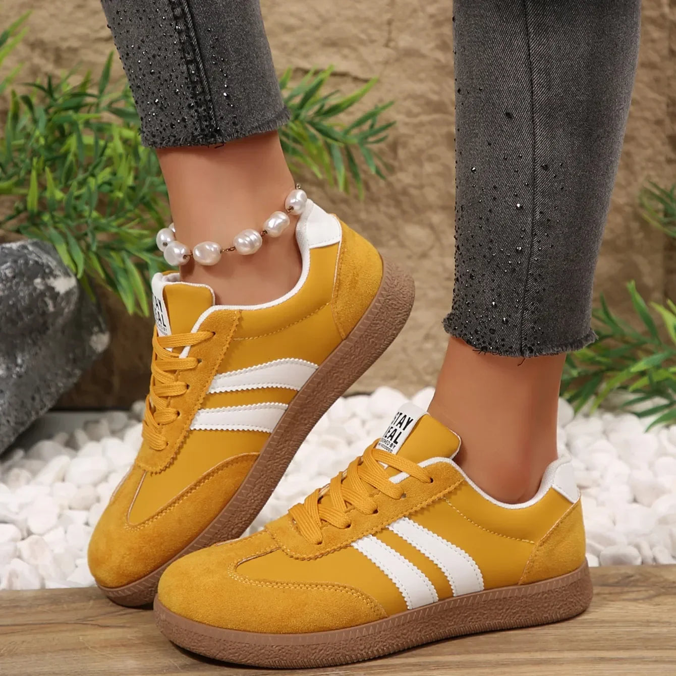 Yellow suede leather slip-on sneakers with white stripes and brown textured soles for casual daily wear.
