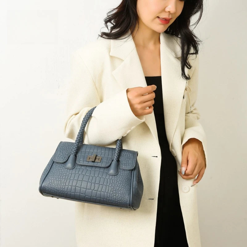 Blue faux leather structured bag with croc-embossed pattern, braided handles, and metal clasp for everyday use.