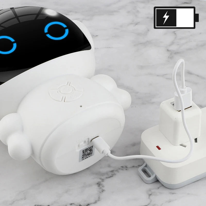 White plastic rechargeable education robot with glowing blue eyes, charging on a marble surface.