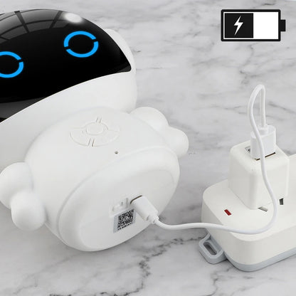 White plastic rechargeable education robot with glowing blue eyes, charging on a marble surface.