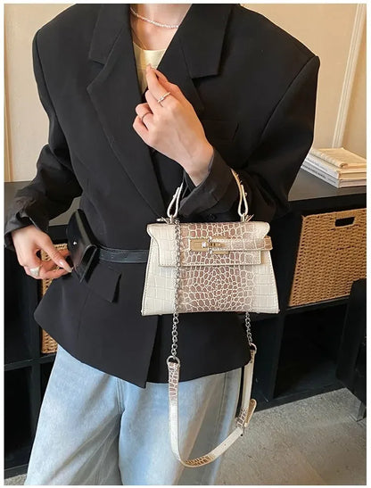 White faux leather crossbody bag with a textured pattern and silver chain for organizing baby essentials on the go.