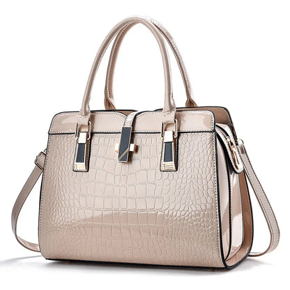 Beige patent leather crocodile-pattern handbag with top handles, crossbody strap, and central clasp.