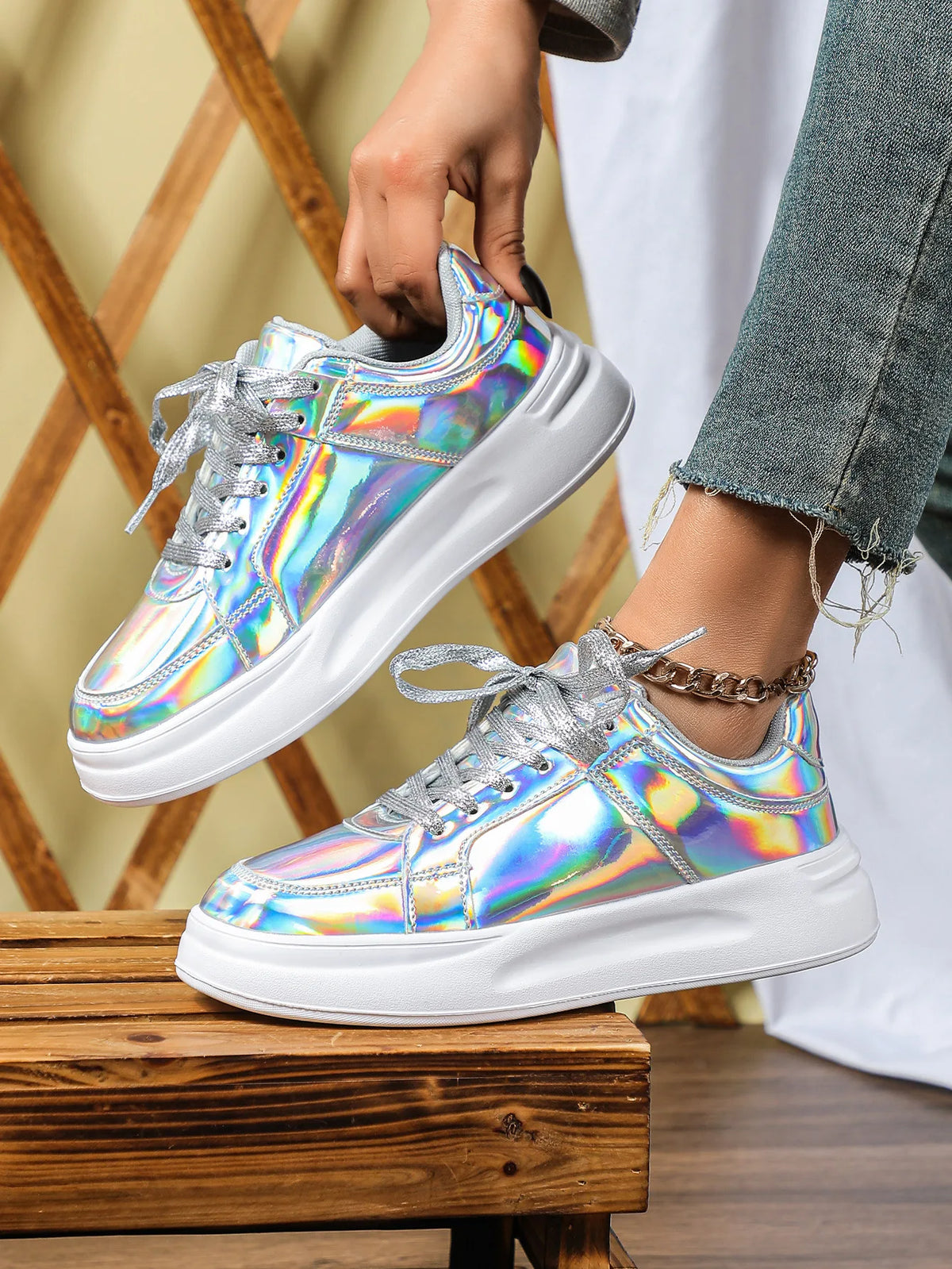 Holographic metallic lace-up sneakers with chunky white soles and shimmering silver laces.