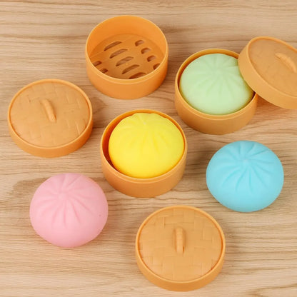 Multi-colored squishy dumpling and bun fidget toy set in plastic bamboo steamers for stress relief.