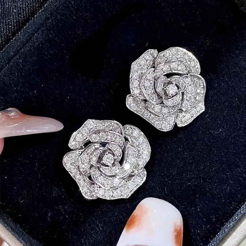 Silver camellia flower earrings paved with sparkly zircons in a layered rose design.