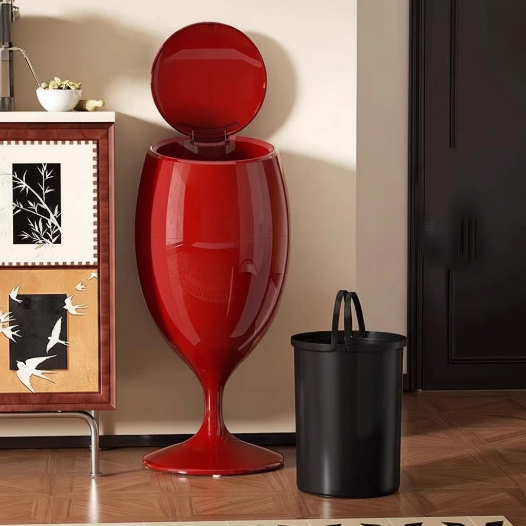 Glossy red wine-glass-shaped trash can with open lid, beside a black inner bucket.