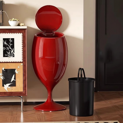 Glossy red wine-glass-shaped trash can with open lid, beside a black inner bucket.